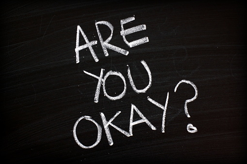 The words Are You Okay written by hand in white chalk on a blackboard