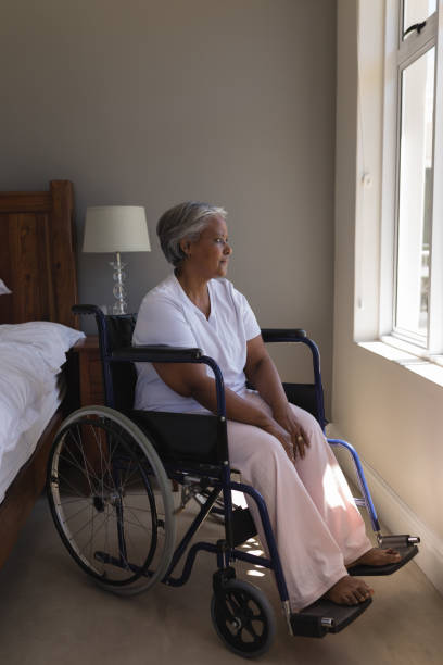 istock Disabled senior woman looking through window at home 1133769416