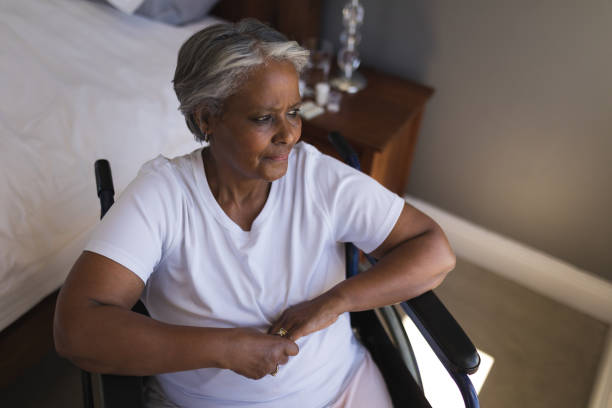 Disabled senior woman looking through window at home