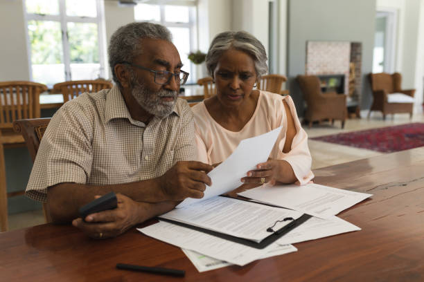 seniorenpaar diskutiert zu hause über rechnungen - document lifestyles senior couple female stock-fotos und bilder