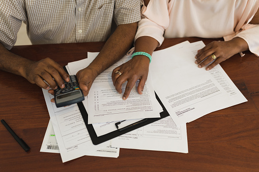Mid section of senior  African American couple looking at invoices and using a calculator at home