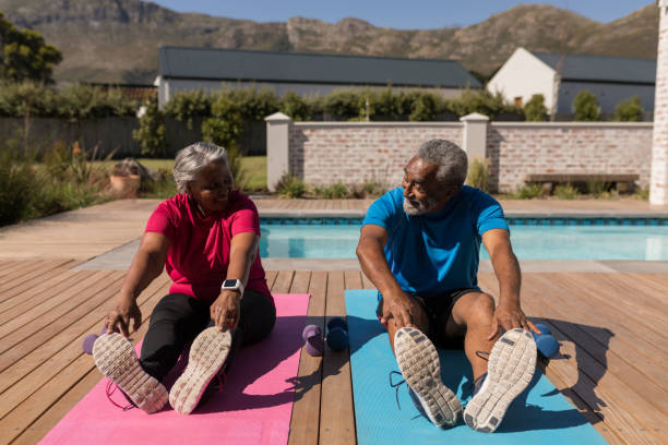 seniorenpaar, das dehnübungen im hinterhof des hauses durchführt - senior adult exercising aging process instructor stock-fotos und bilder