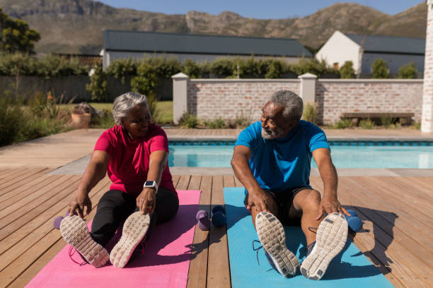 coppia senior che esegue l'esercizio di stretching nel cortile di casa - senior adult senior couple exercising african ethnicity foto e immagini stock