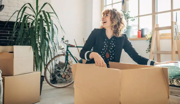 One woman, young lady moved into her new apartment, unpacking boxes alone.