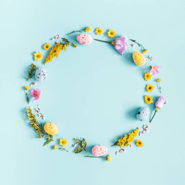istock Easter eggs, purple and yellow flowers on blue background. Flat lay, top view, copy space, square 1133779430