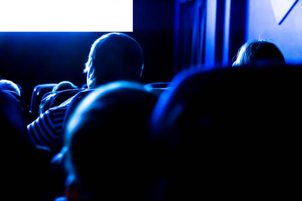istock People in the cinema watching a movie. Blank empty white screen 1133779649