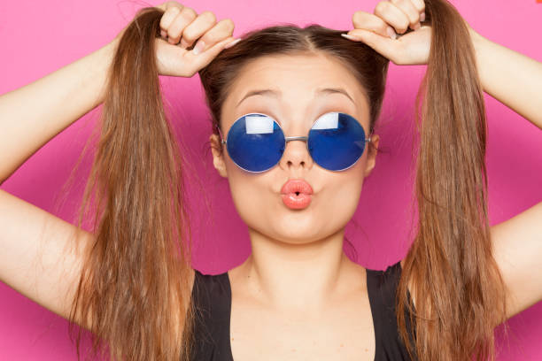 young funny girl with ponytail on pink background