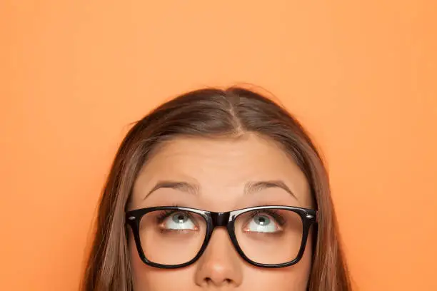 Photo of half portrait of a young girl with glasses looking up