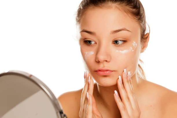 istock young girl applying face cream on white background 1133781853