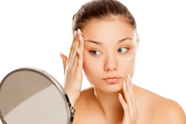 istock young girl applying face cream on white background 1133781855