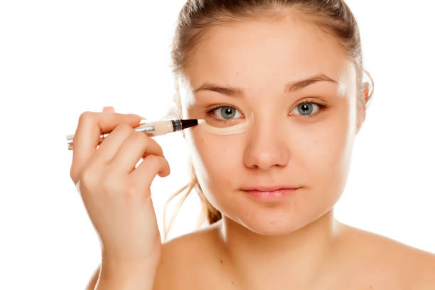 istock young girl applying conceler on white background 1133781864