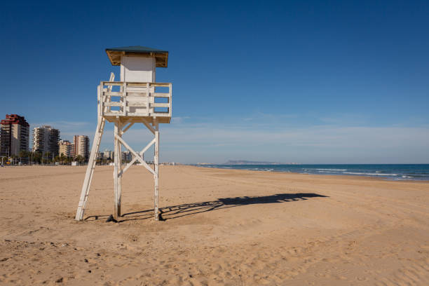 Lifeguard watch tower on empty nice beach with Gandia in background