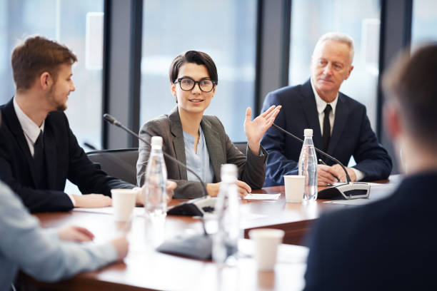 Business Seminar Portrait of young businesswoman speaking to microphone during group discussion in conference room, copy space press conference photos stock pictures, royalty-free photos & images