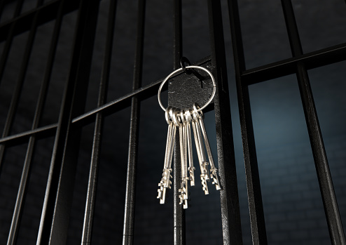 A closeup of the lock of a  jail cell with iron bars and a bunch of key in the locking mechanism with the door open - 3D render