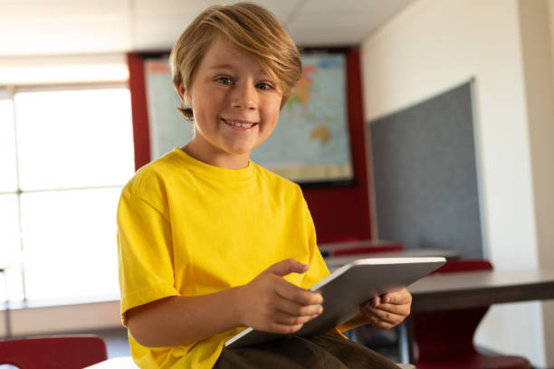 istock Happy boy with digital tablet sitting over desk and looking at camera in a classroom 1133783869