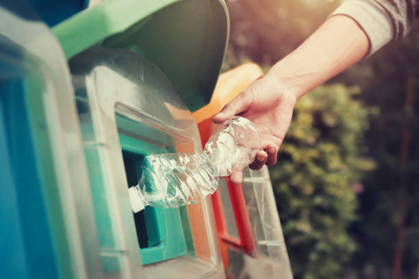 istock people putting plastic bottle in to recycle bin at park 1133784702