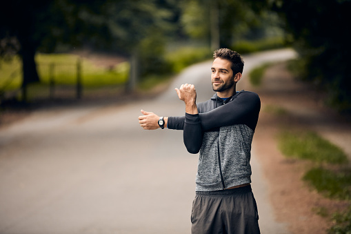 Shot of a sporty man starting his exercise routine with stretching exercises