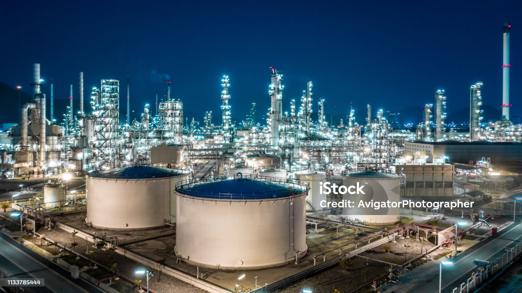 Oil refinery plant from industry zone, Aerial view oil and gas industrial, Refinery factory oil storage tank and pipeline steel at night. Industry Stock Photo