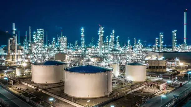 Photo of Oil refinery plant from industry zone, Aerial view oil and gas industrial, Refinery factory oil storage tank and pipeline steel at night.