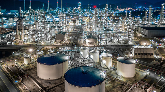 Oil refinery plant from industry zone, Aerial view oil and gas industrial, Refinery factory oil storage tank and pipeline steel at night.