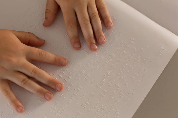istock Blind boy hands reading a braille book in classroom 1133786449