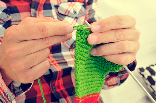 closeup of a young man knitting