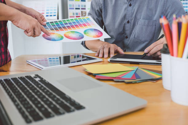 istock Teamwork of young creative designers working on project together and choose color swatch samples for selection coloring on digital graphic tablet at workspace 1133788309
