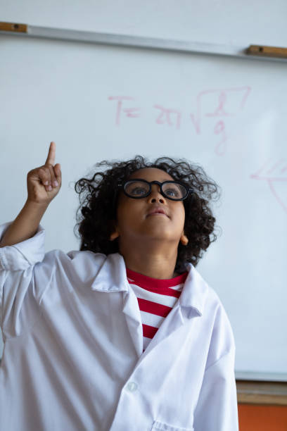 istock Schoolboy pointing finger up in laboratory 1133789125