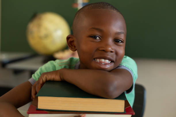 istock Schoolboy leaning on books at desk in a classroom 1133789994