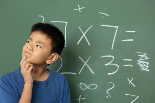 istock Thoughtful schoolboy doing math on green chalkboard in a classroom 1133790750