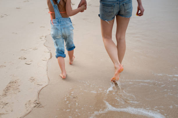 istock Mother and daughter walking on the beach 1133791524