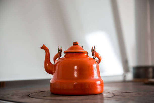 Orange vintage teapot on a wood burning stove.