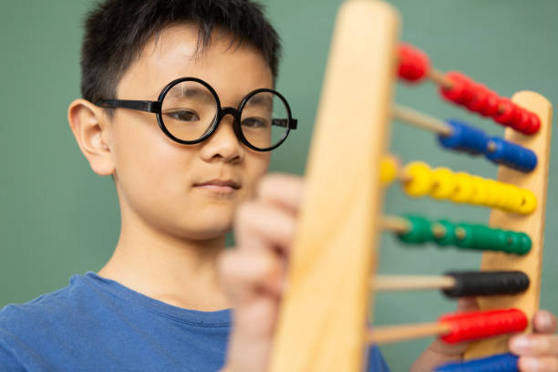 istock Boy learning math with abacus against green chalkboard in a classroom 1133792599