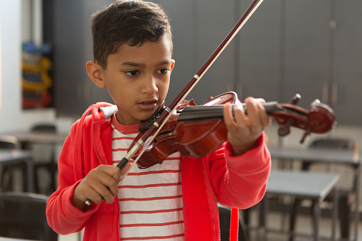 Schoolboy playing violin in classroom