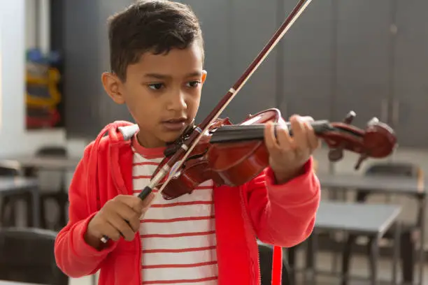 Photo of Schoolboy playing violin in classroom