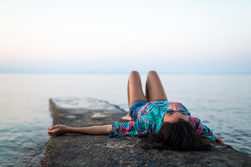 Woman lying on the pier,  enjoying by the sea alone, Halkidiki, Greece