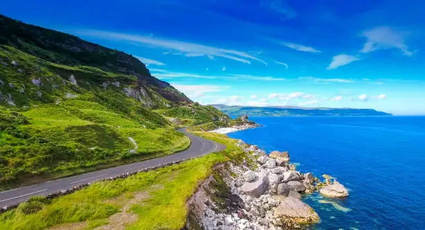 The road and the coastal rocks in the village of Cushendun the road along the mountain side fronting the blue sea in the village