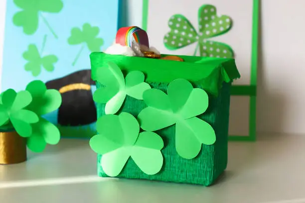 DIY leprechaun trap with gold coins, rainbow and green ladder St Patricks Day background. Gift Idea, decor Saint Patricks Day. Step by step. Child kid craft process. Top view. Irish holiday.