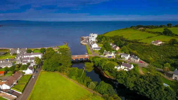 The aerial landscape shot of the greeny coastal village Cushendun. Lots of trees and green fields on this small coastal village in North Ireland in Ireland