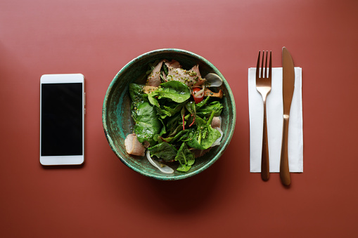 Plate with salad and empty screen of smartphone on the table, flat lay