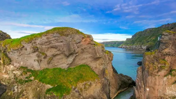 The amazing landscape view of the Carrick-a-Rede Rope Bridge and the big blue ocean on the islands in Ireland