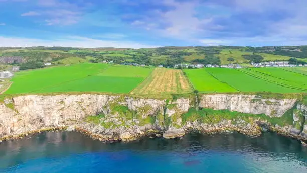 Amazing view of the Carrick-a-Rede cliff in Ireland the green mainland facing the big ocean and the blue sky on a fine day in Ireland