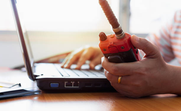 istock Female radio operator using Walkie - Talkie to communicate with other people and typing on laptop. 1133803169