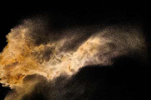 Explosión de arena dorada aislada sobre fondo negro. Nube de arena abstracta. Salpicadura de arena de color dorado contra fondo oscuro. Onda amarilla de la mosca de la arena en el aire. photo