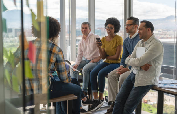 istock Young diverse group of professionals at a coworking office sitting on tablets while discussing business smiling 1133804297