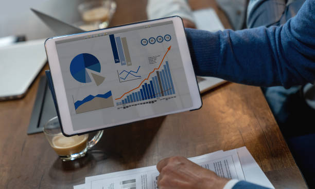 istock Close up of unrecognizable businessman holding a tablet with graphics on screen 1133808050