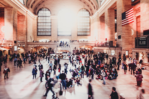 People stand in Grand Central Terminal in New York City, USA on a sunny day.