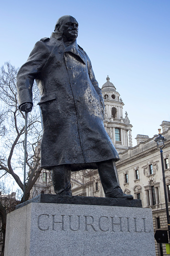 Churchill Statue shows Winston Churchill standing with his hand resting on his walking stick and wearing a military greatcoat, Parliament Square, London, England, February 12, 2018.