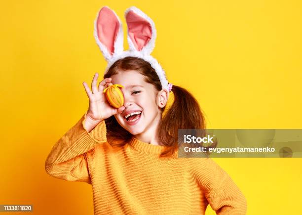 Lustige Fröhliche Kindermädchen Mit Ostereiern Und Kaninchenohren Auf Gelb Stockfoto und mehr Bilder von Ostern