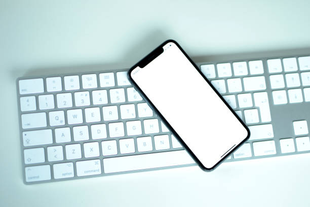 istock A smartphone with white blank screen is left on a modern keyboard 1133813253